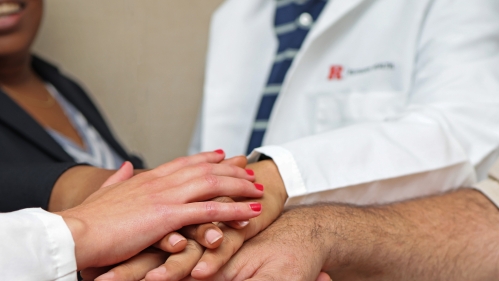 People stack their hands to signify teamwork and collaboration or community