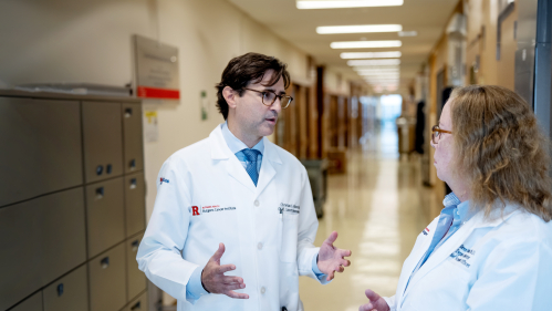 Researchers Christian Hinrichs and Eileen White talk in a hallway at Rutgers Cancer Institute.