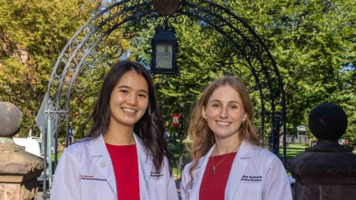 Rutgers Health medical students Angela Zhao (left) and Hailey Sulzbach stand before the Class of 1902 Memorial Gateway on the College Avenue campus.
