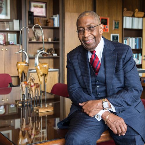 Dean Robert L. Johnson leans on a desk in his office. 